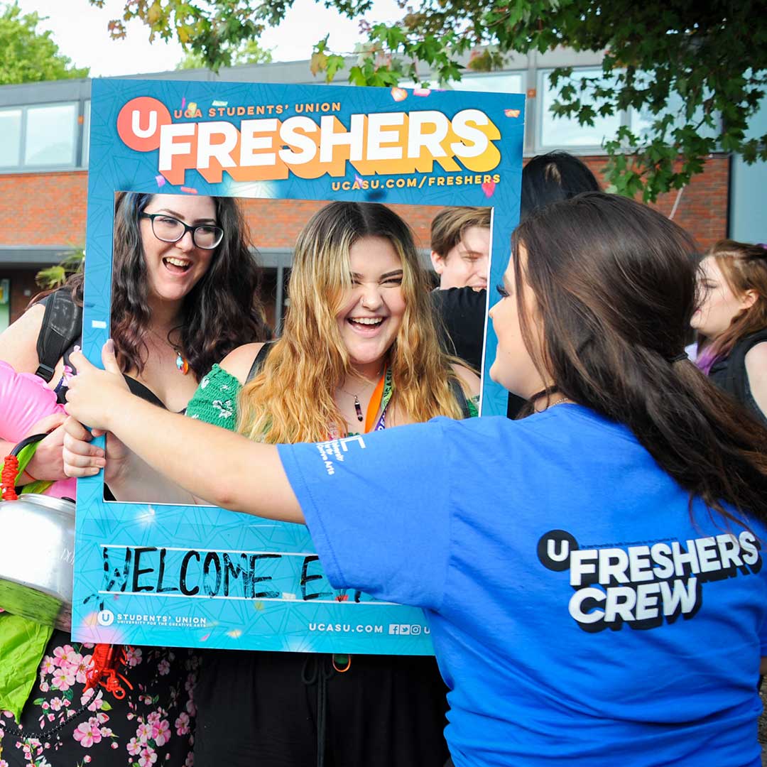 A photograph of students at Freshers, posing in a photo frame